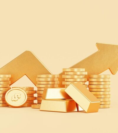 Gold coins and bars with an arrow going upwards in the background.