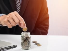 A person dropping a coin into a jar.