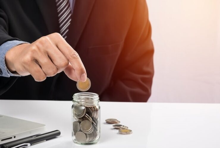 A person dropping a coin into a jar.